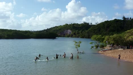 dolly em tiro aéreo drone passando sobre um pequeno grupo de pessoas brincando na água do sinuoso grande rio tropical gramame perto da praia tropical capital de joão pessoa na paraíba, brasil