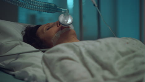 병원 클로즈업에서 맥박 옥시미터 손. 산소 마스크를 착용하여 누워있는 노인 여성.