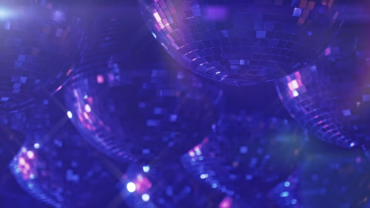 Molteplici sfere da discoteca che riflettono luce viola e blu