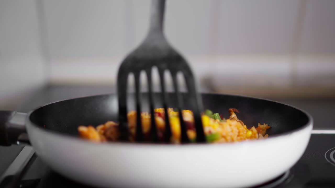 Close up shot of Stirring food in a frying pan on the top of the Stove