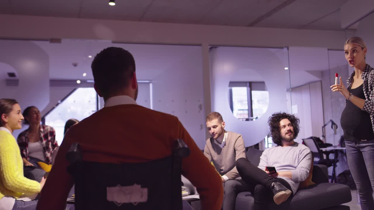 Disabled businessman in a wheelchair at work in modern open space coworking office on team meeting. Effective teamwork and inclusion in a startup business.