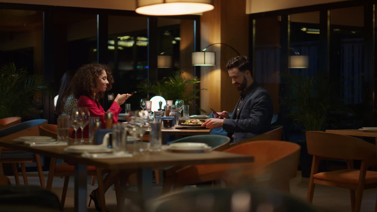 To elskende tager billeder med mobiltelefon på restaurant. Parret nyder en middagsdate.