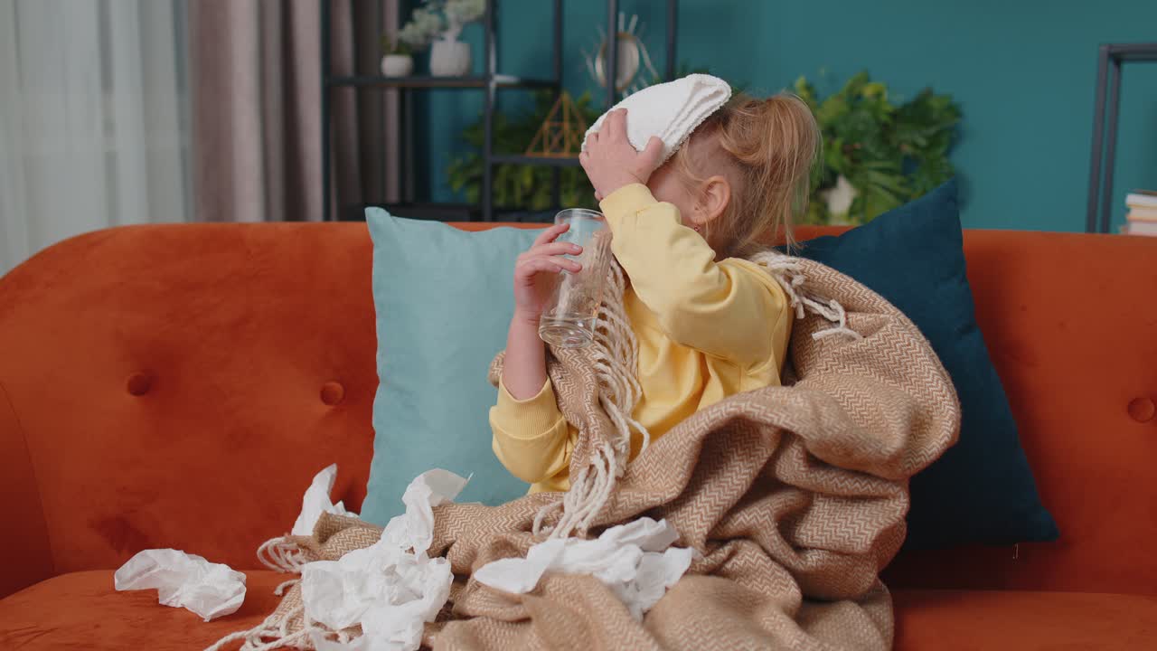 Child girl in plaid suffering from cold or allergy drinking medicine pill tablet water at home room