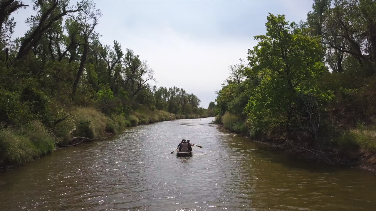 Carrellata lenta di persone che fanno kayak lungo un fiume marrone dopo la pioggia