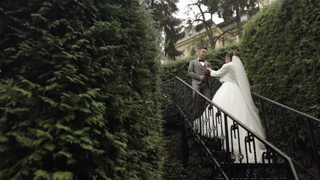 Newlyweds,-caucasian-groom-with-bride-stay-on-stairs-in-park,-wedding-couple,-man-and-woman-in-love