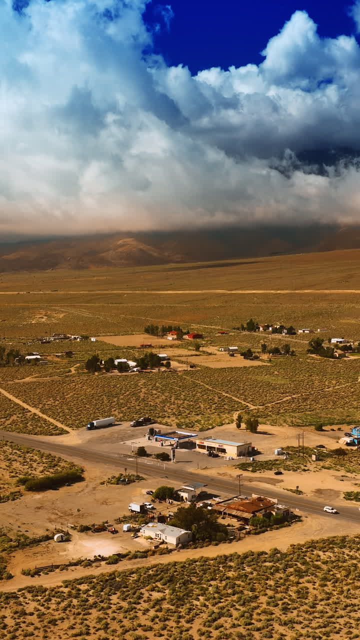 A little settlement located in the dry desert near the highway. White cloudscape covering the mountains at backdrop. Vertical video