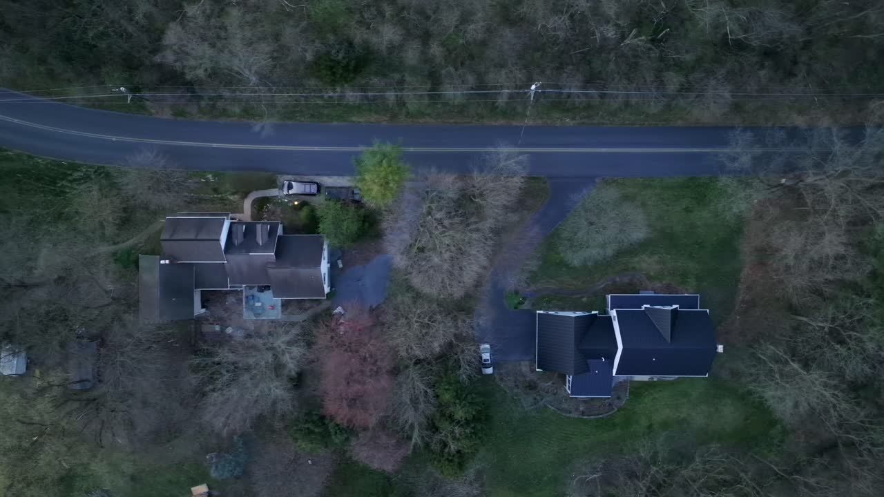 Aerial truck shot top down of houses and road lined with trees