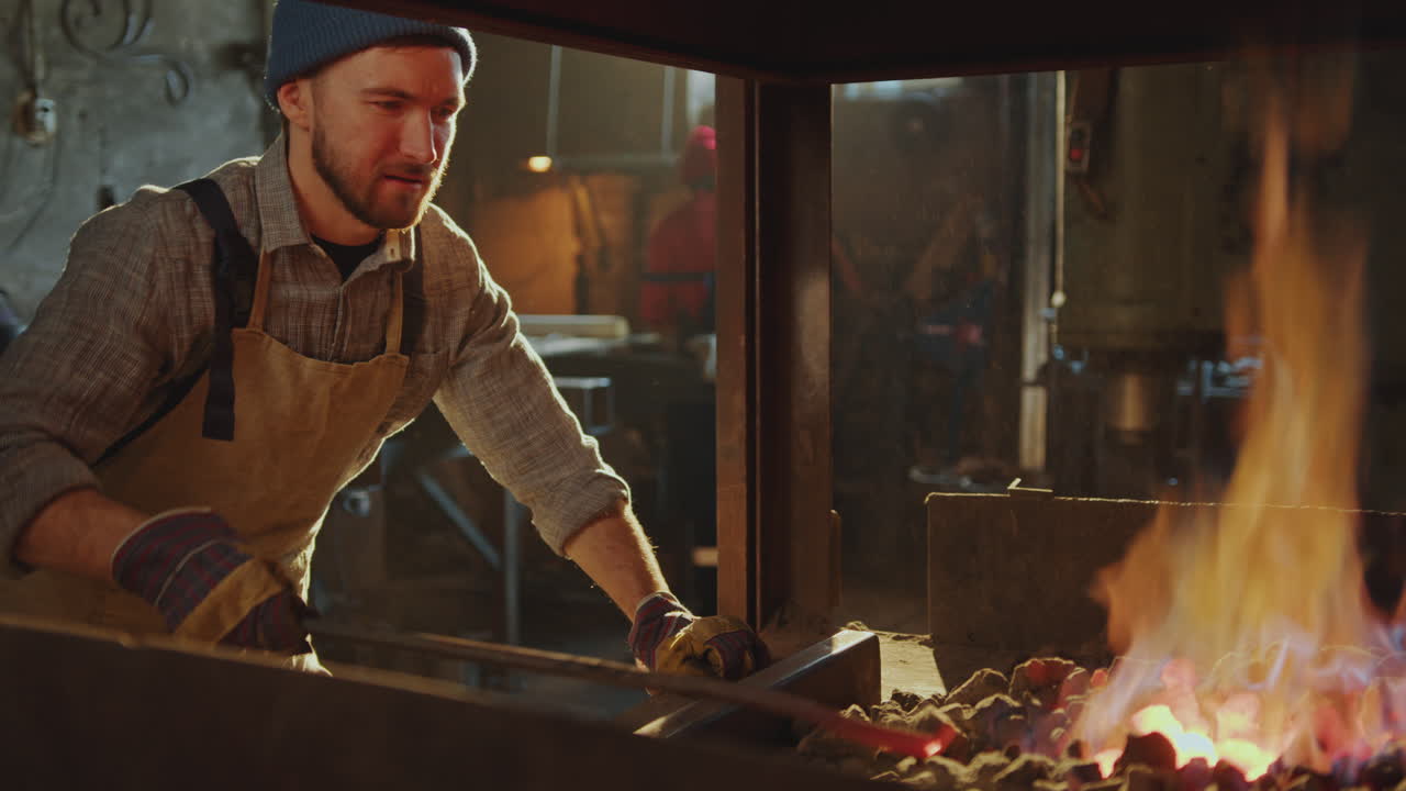 herrero moviendo carbón para mantener el fuego ardiendo en la forja