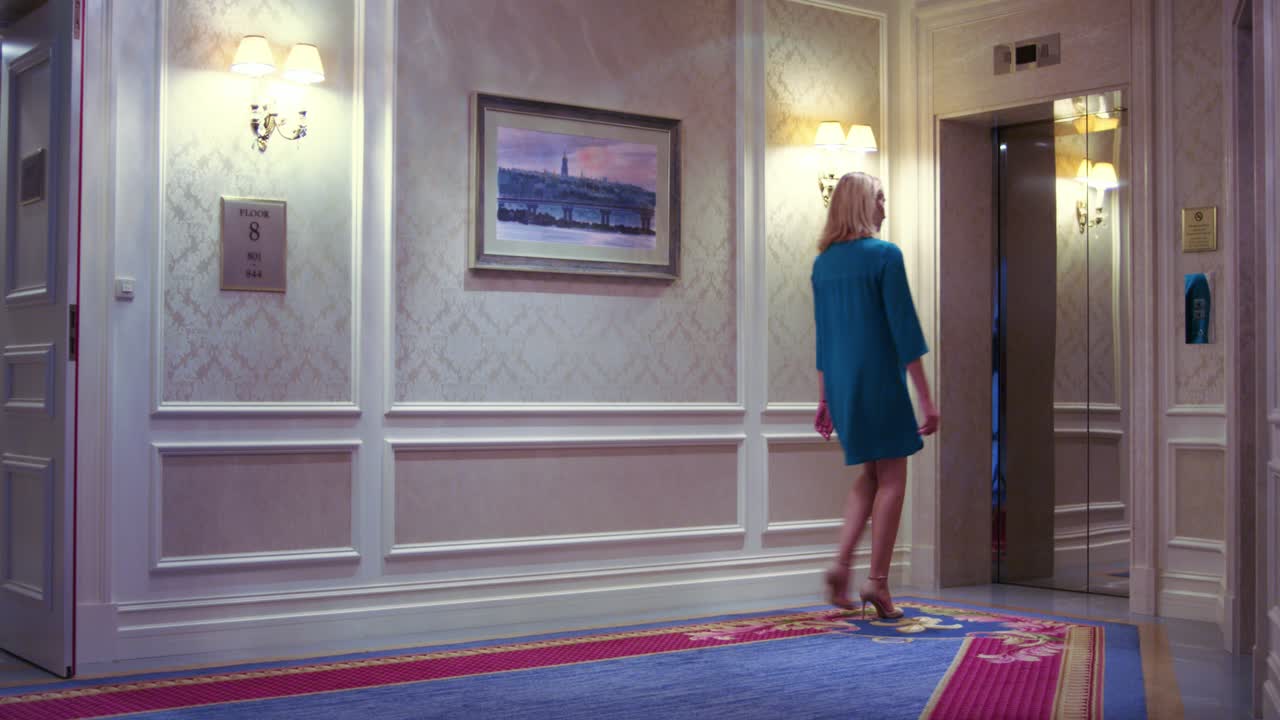 젊은 여성이 문을 들어 올리고 호텔에 전화하기 위해 버튼을 누르고 있습니다.