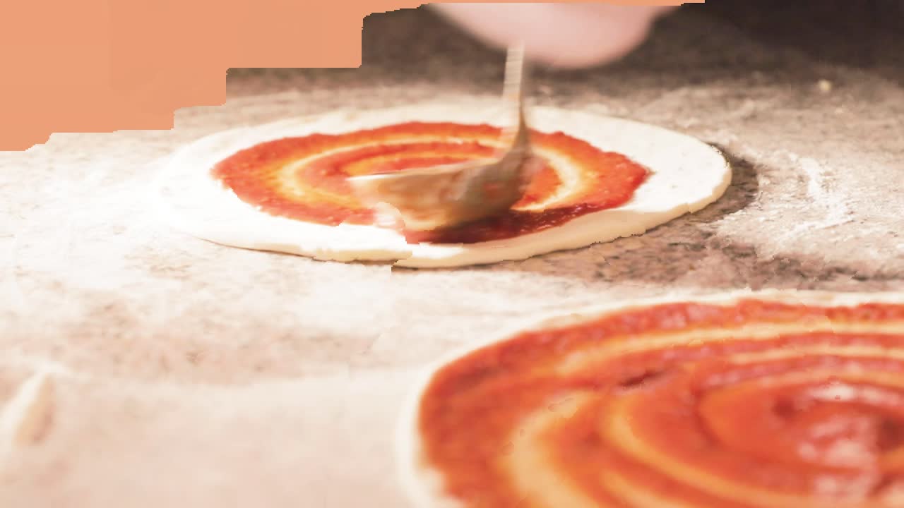 Cuoco che prepara l'impasto per la pizza con salsa di pomodoro per il forno in una cucina luminosa