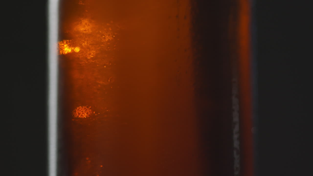 차가운 맥주 또는 탄산음료의 회전하는 병에 응축 방울의 가까운 을 끌어