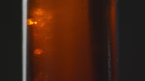 pull focus close up shot of condensation droplets on revolving bottle of cold beer or soft drink