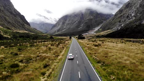 white audi a4 drives along the spectacular milford road on the left hand side in new zealand.