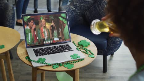 Person at bar using laptop making st patrick&#039;s day video call with friends at another bar