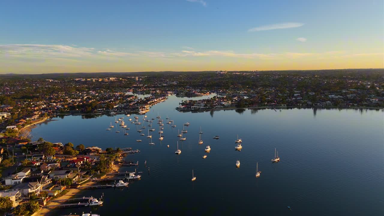 Wide aerial establishing Taren Point and Sylvania Waters with bridges, boats, and residential areas at sunset golden hour, Sydney NSW Australia