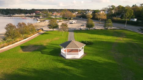 Aerial-rotational-view-of-isolated-gazebo-amidst-lush-green-garden-beside-beautiful-lake