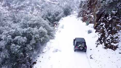 jeep driving off-road on a cliffside in a snow storm