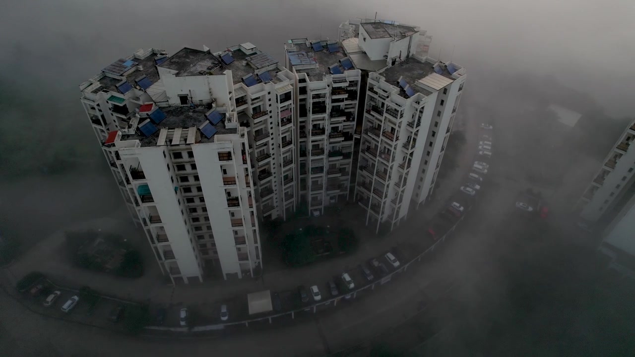 Ripresa con drone di torri di appartamenti circondate da una fitta nebbia mattutina.