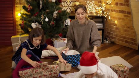 Madre-E-Hijos-Envolviendo-Regalos-De-Navidad-En-El-Suelo.