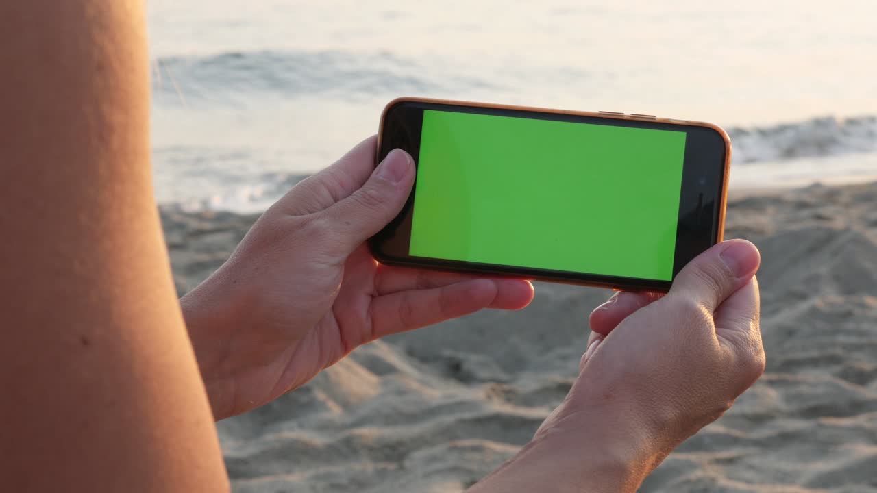 pantalla verde teléfono inteligente en la mano de la mujer por el mar 4k video