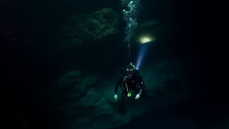 scuba diver exploring a dark underwater cave