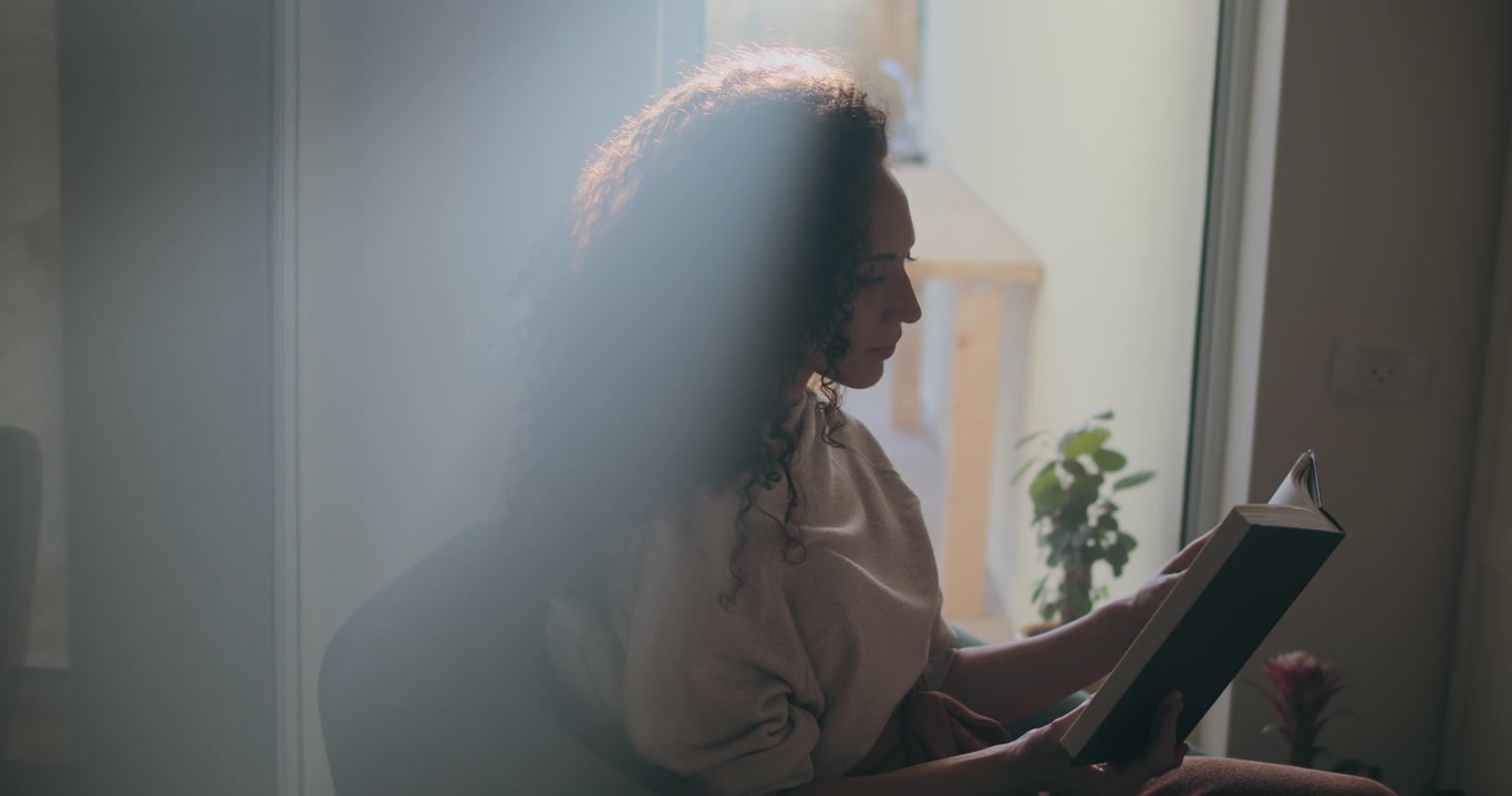 Sunlight beam over woman reading a book