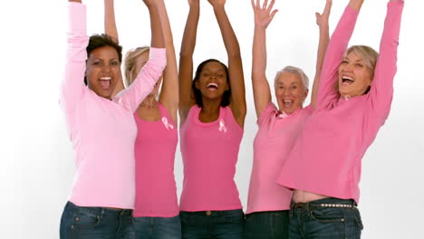 group of cheerful women raising arms for breast cancer awareness