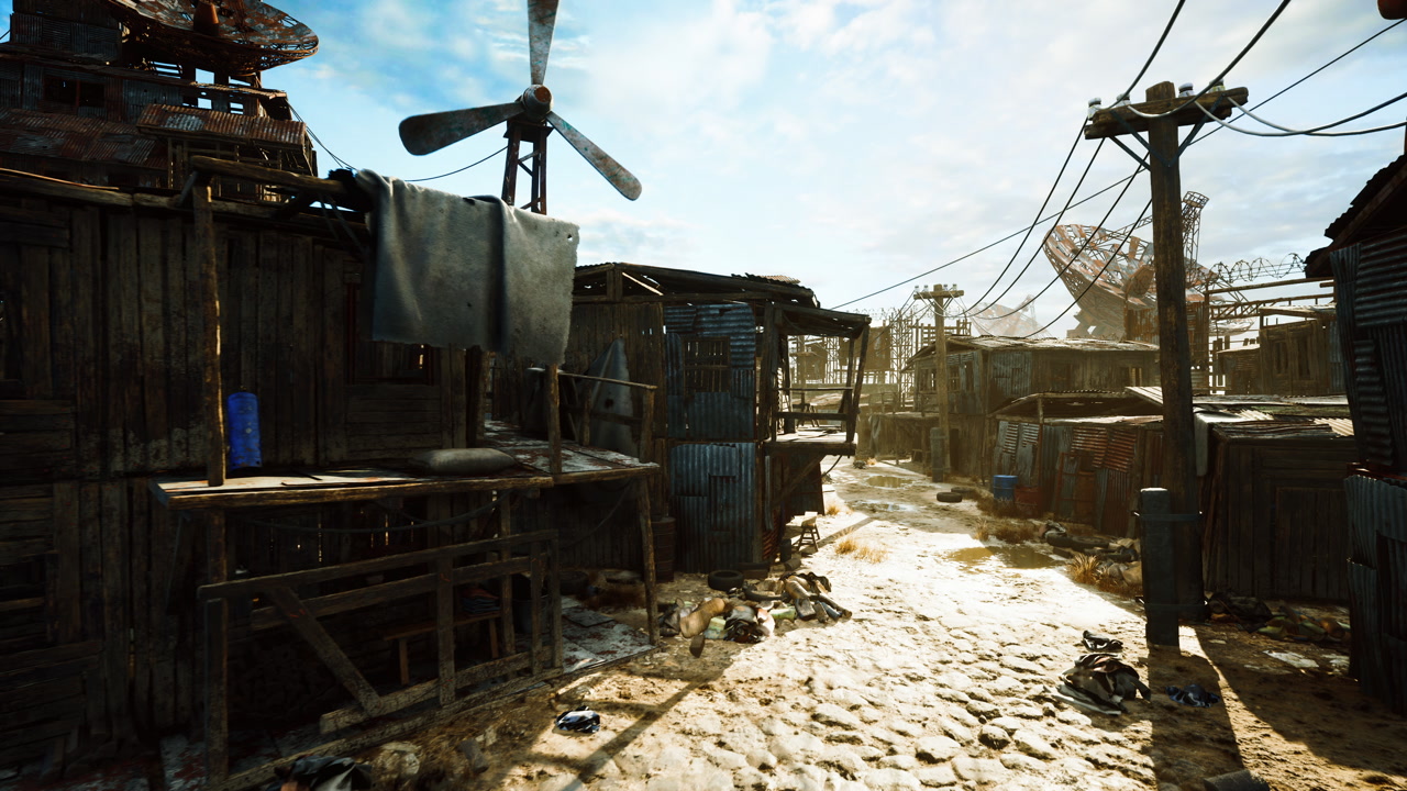 Sunlit muddy pathway amid makeshift shelters and weathered structures