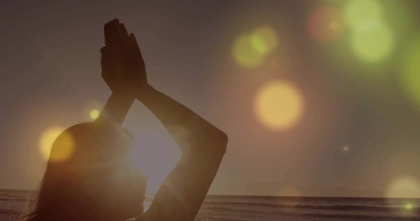 Silueta de una mujer practicando yoga en la playa al atardecer