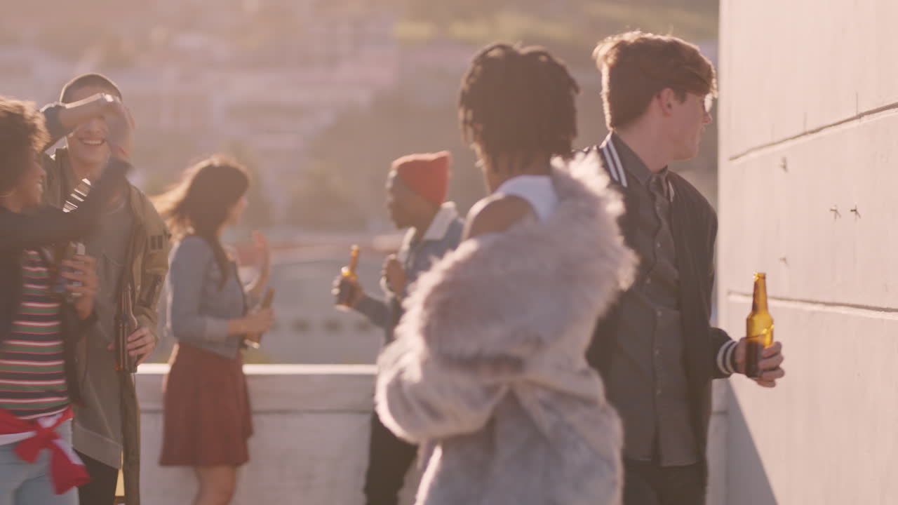 옥상 파티 축하 친구들이 춤추고 여름 휴가를 즐기고 술을 마시고 해가 지는 도시에서  ⁇ 은 주말을 축하합니다.