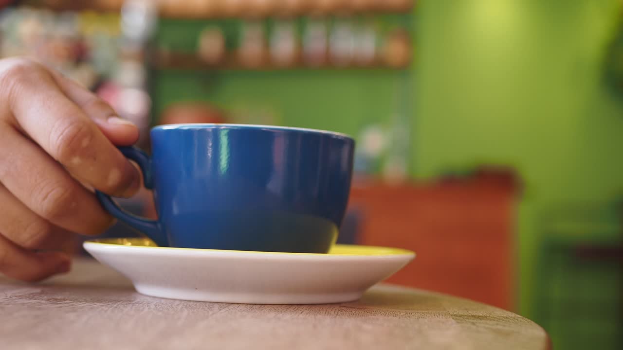 Person holding blue coffee cup in a cafe