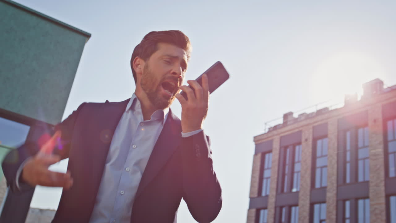 Primo piano di un uomo d'affari infuriato che litiga al telefono in una strada soleggiata