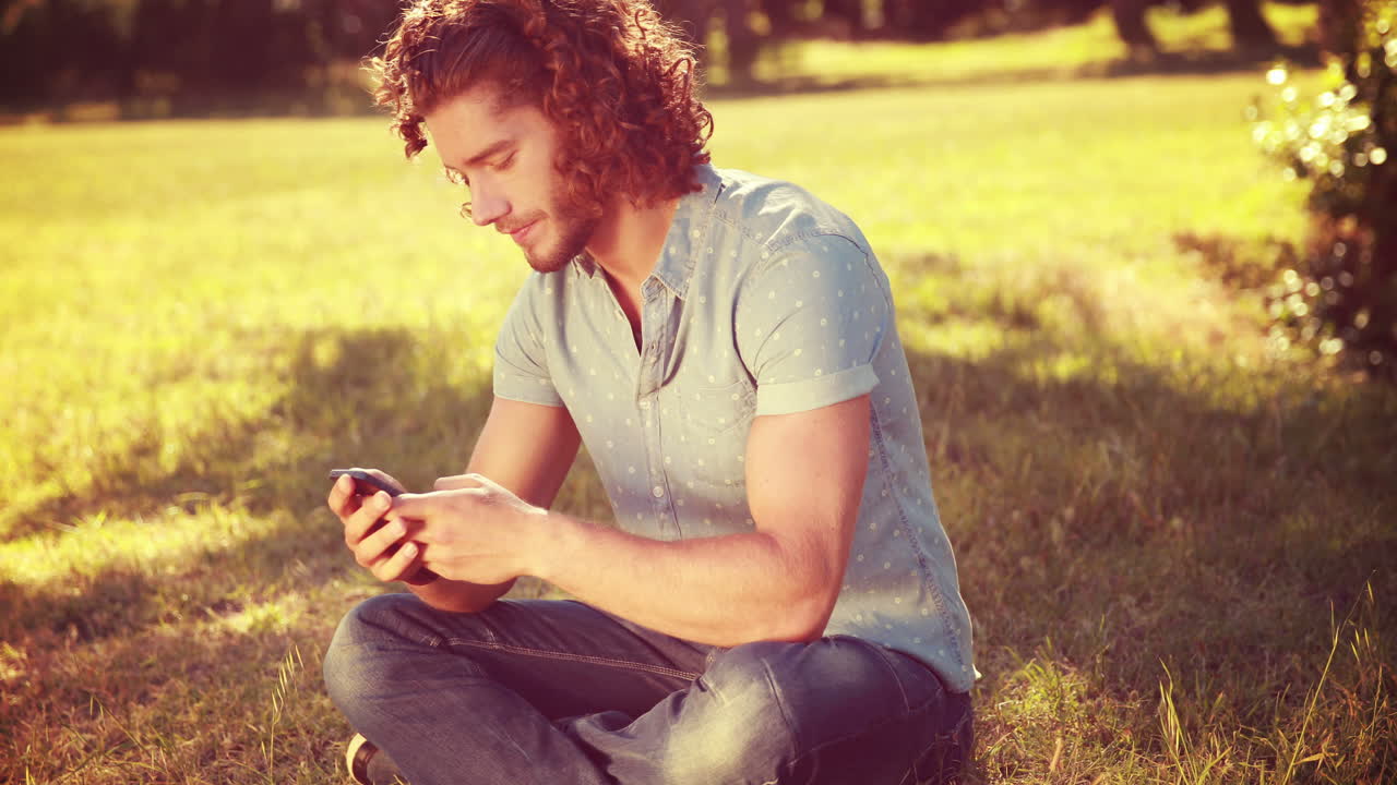 In high quality 4k format young man using smartphone in the park 