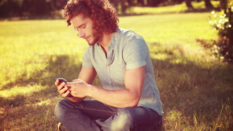 En-Formato-4k-De-Alta-Calidad,-Un-Joven-Usando-Un-Teléfono-Inteligente-En-El-Parque.-