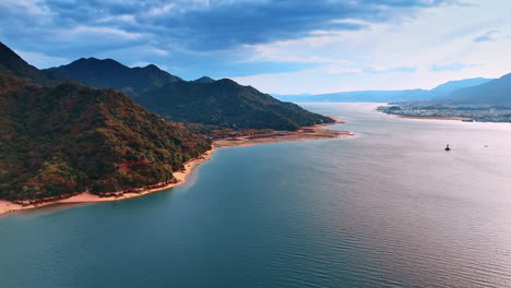 drone footage over the tranquil waterscape surrounded by gorgeous mountains. dark heavy cloudscape covering the sky.