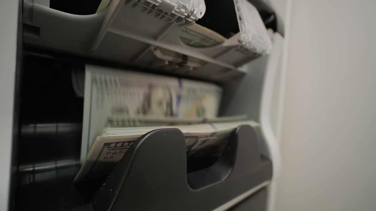 Close-up of a money counting machine processing US dollar banknotes. Represents financial transactions, currency handling, banking, and cash management in a business context