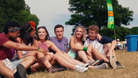 friends sitting on grass watching a gig at a music festival