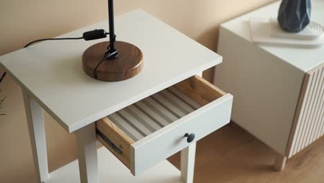 white nightstand with open drawer and lamp