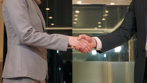 close up woman and man hands business people partners shaking successful corporate partnership deal welcoming opportunity in modern glass office agreement professional greeting meeting partners.