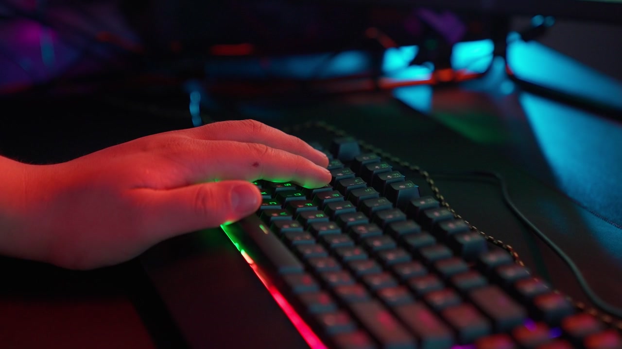 Mano di un giocatore che preme i tasti su una tastiera RGB illuminata