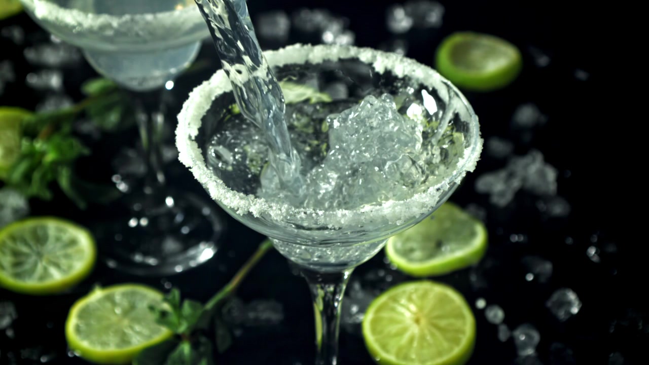 Cocktail rinfrescante versato in un bicchiere da Margarita bordato di zucchero con ghiaccio e lime