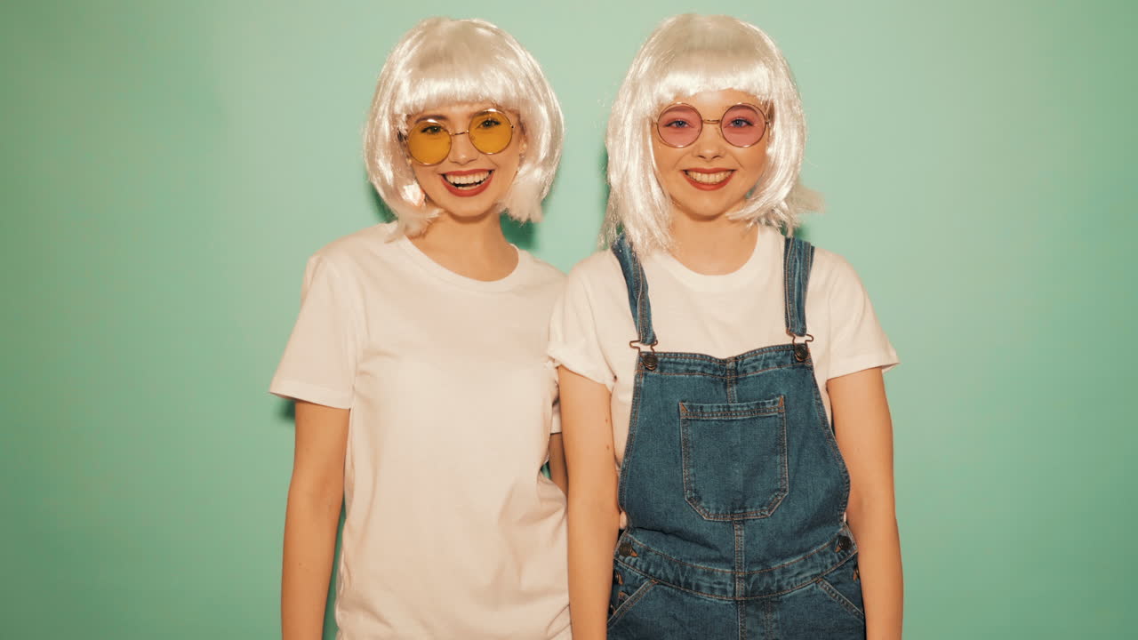 dos hermanas sonriendo en monos de mezclilla y camisetas blancas