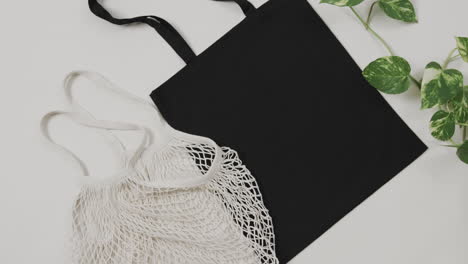 primer plano de bolsas blancas y negras con planta verde sobre fondo blanco, con espacio de copia, cámara lenta
