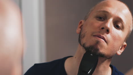 guy-in-black-shaves-beard-with-modern-machine-in-bathroom