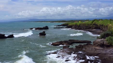 Foamy-Waves-Splashing-Rugged-Coastline-In-Bali,-Indonesia---aerial-drone-shot