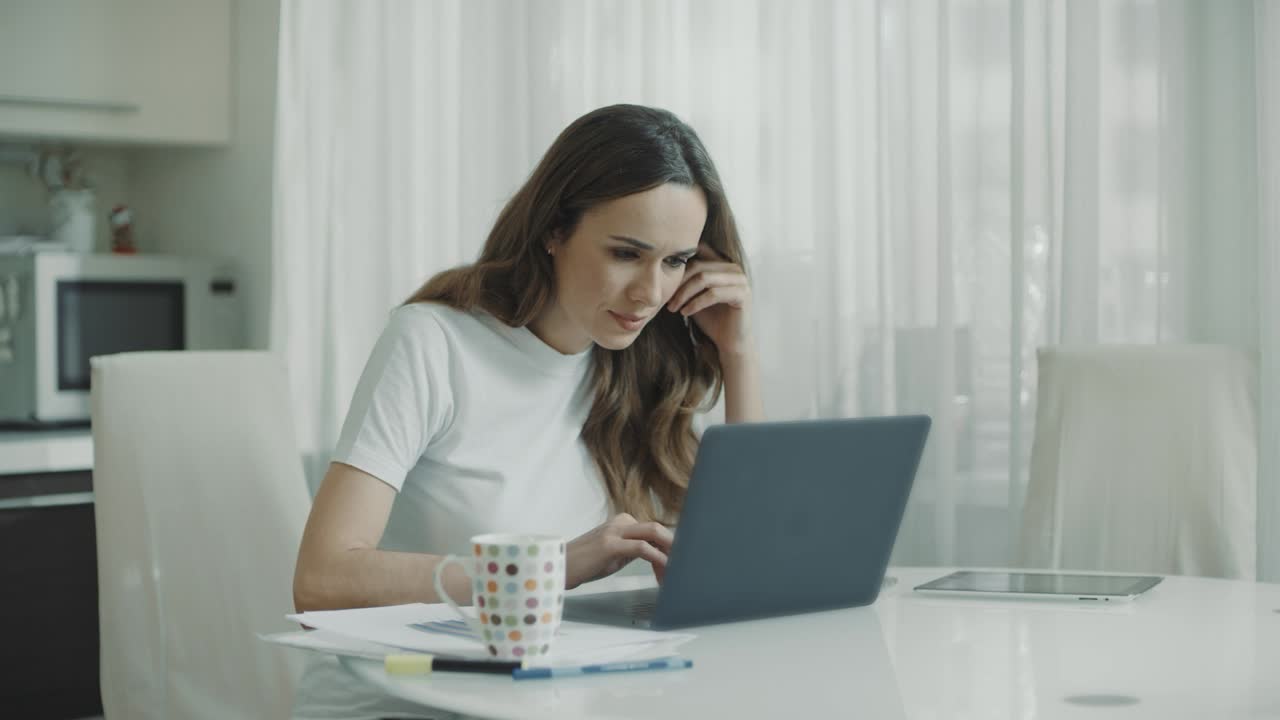 mujer joven usando una computadora portátil en la cocina. mujer de negocios trabajando en un cuaderno