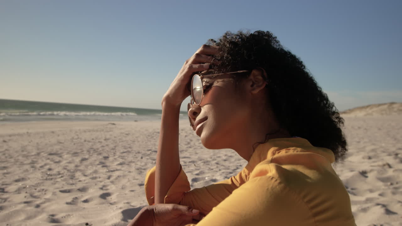 Femme en lunettes de soleil se détendant sur la plage 4K
