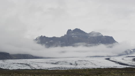 tourist van drives past the dramatic mountain landscapes around icelands golden circle in fjallsárlón