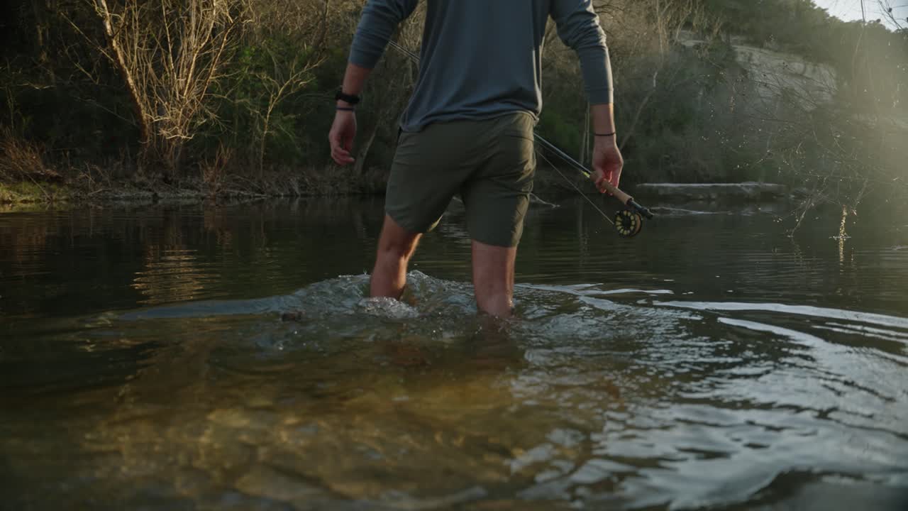 Mannelijke vliegvisser stapt in zonovergoten meerwater met sandalen, close-up, slow motion
