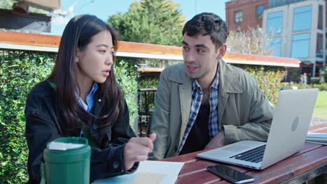 colleagues working with laptop at outdoor space